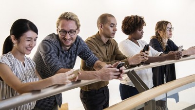 5 people using the Limitless app on their phones whilst leaning on a fence.